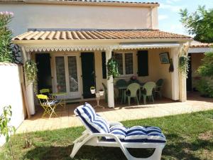 een patio met een stoel en een tafel en stoelen bij Le clos de la Plage - Villa vintage avec jardin privatif- 500m de la plage - 6 personnes in Dolus d'Oléron