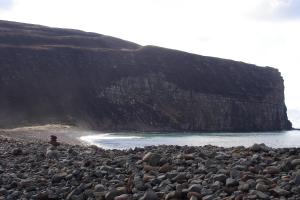 una persona sentada en una playa rocosa cerca del agua en Bellavista Guest House en Kirkwall