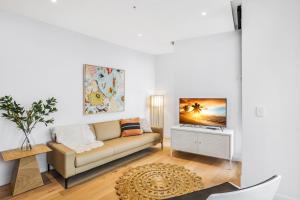 un soggiorno con divano e TV di KOZYGURU FORTITUDE VALLEY DESIGNER GRADE 2 BED APT FREE PARKING QFV179-1401 a Brisbane