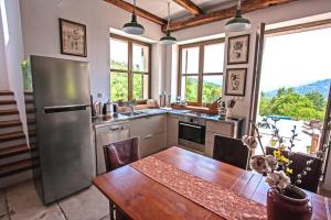 a kitchen with a table and a stainless steel refrigerator at Villa Bazjaki - Beautiful stone villa in Istria with private pool in Livade