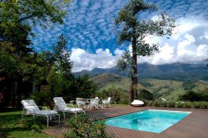 een patio met een tafel en stoelen naast een zwembad bij Casa da Colina Chalés in Visconde De Maua