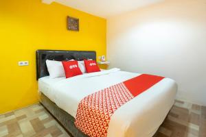 1 dormitorio con 1 cama grande con almohadas rojas en OYO 3782 Gunung Anyar en Surabaya