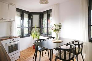a kitchen with a table and chairs and windows at Modern Cozy Apartment in Kyustendil