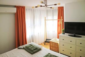 a bedroom with a bed and a dresser with a television at Modern Cozy Apartment - NEW in Kyustendil