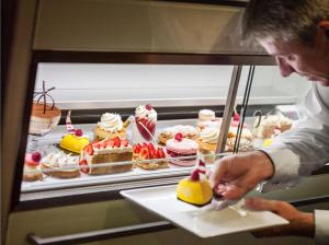 a man standing in front of a buffet of desserts at Hôtel Juana in Juan-les-Pins