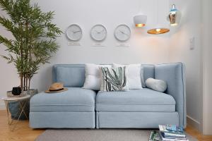 a blue couch in a living room with clocks on the wall at Jasmine Loft in Porto