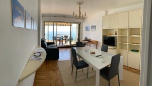 Appartement avec vue mer sur la Promenade des Anglais في نيس: مطبخ وغرفة معيشة مع طاولة وكراسي