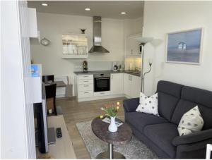 a living room with a blue couch and a kitchen at Norderneytraum Kampstr. Wohnung 1 in Norderney