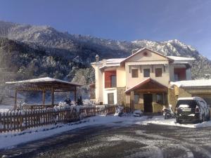 una casa con una valla en la nieve con una montaña en Villa Alexandra en Grevena