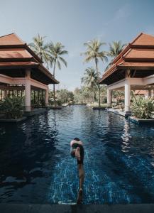a man and woman standing in a swimming pool at a resort at Banyan Tree Phuket in Bang Tao Beach