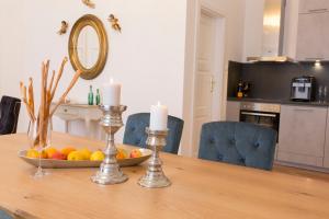 a dining room table with a bowl of fruit and candles at Palais Gutenberg la Ville in Klagenfurt