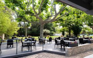 un patio con mesas y sillas en un parque en Logis Hotel Restaurant SPA Les Oliviers, en Loriol-sur-Drôme