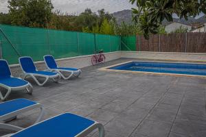 a group of blue chairs and a swimming pool at Casa Rural El Níspero in Cortes de la Frontera