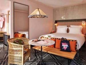パリにあるMama Shelter Paris Westのベッド、テーブル、椅子が備わるホテルルームです。