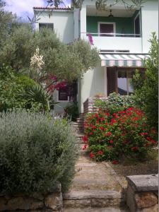 una casa blanca con flores rojas delante en Apartments Miletić, en Ždrelac