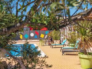 un complexe avec une piscine, des chaises et des plantes dans l'établissement greet Hotel Marseille Provence Aéroport, à Vitrolles