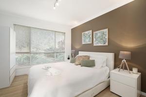 Un dormitorio con una gran cama blanca y una ventana en Central Coast Escape, en Point Clare