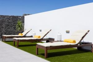 two chaise lounges with yellow pillows on the grass at TEBAR BEACH in Yaiza