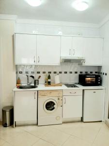 a kitchen with white cabinets and a washing machine at Central Estudio Málaga in Málaga