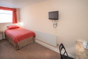 1 dormitorio con 1 cama y TV en la pared en The Rollason Hotel, en Birmingham