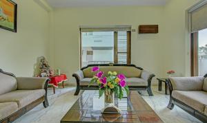 una sala de estar con un jarrón de flores sobre una mesa en Itsy By Treebo - Swastika Inn Sector 26, en Noida