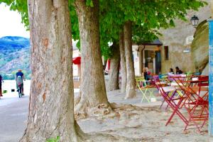 a row of trees with tables and chairs on a sidewalk at Smile Apartments zum Goldenen Strauß in Dürnstein