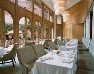 a restaurant with white tables and chairs and windows at The Rittenhouse Hotel in Philadelphia