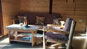 Una sala de estar con un sofá, una mesa y sillas. en Brvnara Dolina jela, en Bajina Bašta
