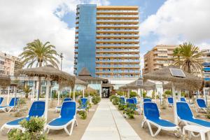una fila de sillas y sombrillas azules en una playa en Hotel Yaramar - Adults Recommended en Fuengirola