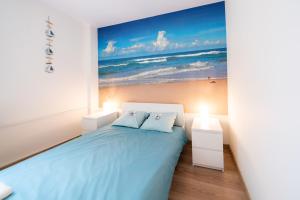 a bedroom with a bed and a painting of the beach at Apartament Blue Sea Gdynia in Gdynia