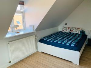 Schlafzimmer mit einem Bett mit blauer Bettwäsche und einem Fenster in der Unterkunft Hyggelig 1.sals lejlighed i Varde midtby. in Varde