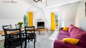 a living room with a purple couch and a table at Wonder Home - Apartamenty w cichej i zielonej części Karpacza - z miejscem na grilla in Karpacz