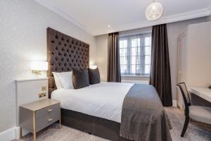 布拉克内尔Easthampstead Park的配有一张大床和一张书桌的酒店房间 更多37张照片