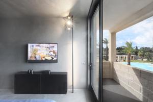 een slaapkamer met een tv aan de muur naast een zwembad bij Masseria Donna Huga in Leverano