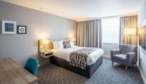 um quarto de hotel com uma cama e uma cadeira em Holiday Inn Ellesmere Port/Cheshire Oaks, an IHG Hotel em Ellesmere Port