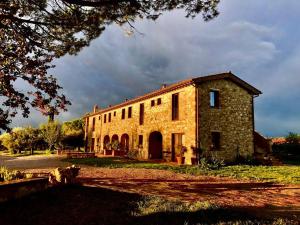 um grande edifício de tijolos com uma árvore em frente em Agriturismo Sole em Trequanda