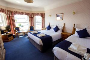 a hotel room with two beds and two windows at Channel View Hotel in Shanklin