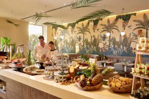a man and woman standing at a buffet table with food at Vincci EverEden in Anavyssos