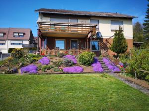 ein Haus mit lila Blumen vor einem Hof in der Unterkunft Ferienwohnung Traumblick in Bad Sachsa