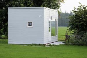 a small white shed with a window in a field at Panorama Box op Camping de Stal in Drijber