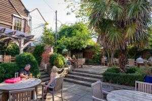 a group of people sitting at tables in a garden at The Sun Inn in Faversham