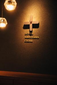 Un cartello su un muro con una croce sopra. di HOTEL KARUIZAWA CROSS a Karuizawa
