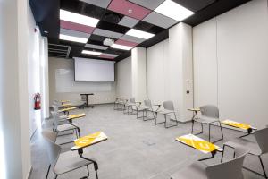 une salle de conférence avec des chaises et un écran de projection dans l'établissement Villa Alojamiento y Congresos - Villa Universitaria, à San Vicente del Raspeig