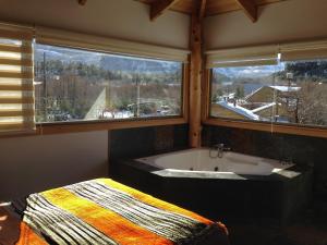 a bathroom with a bath tub and two windows at Refugio Ecobox Andino in Las Trancas