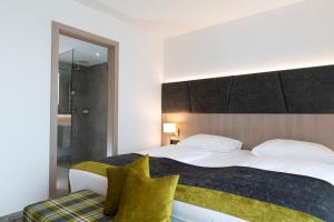 a bedroom with a large white bed with yellow pillows at Hotel Plattenwirt in Klagenfurt