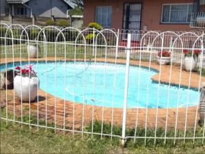 a fence around a swimming pool in front of a house at MS Self-Catering in Pietermaritzburg