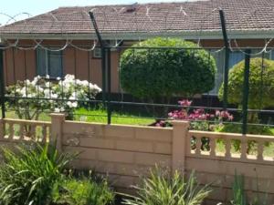 a fence in front of a house with flowers at MS Self-Catering in Pietermaritzburg