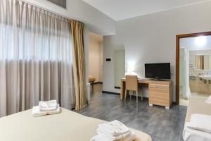 a hotel room with two beds and a desk with a television at Garden Area Roma Eur in Rome