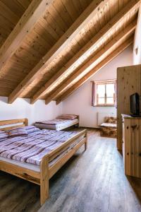 a bedroom with two beds in a room with wooden ceilings at Roubenka u Huvarů in Tachov
