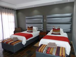 a bedroom with two beds and a chair in it at Opuwo Country Lodge in Opuwo